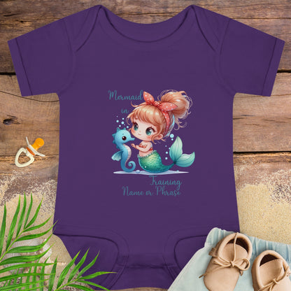 Purple baby onesie with mermaid design on a wooden surface