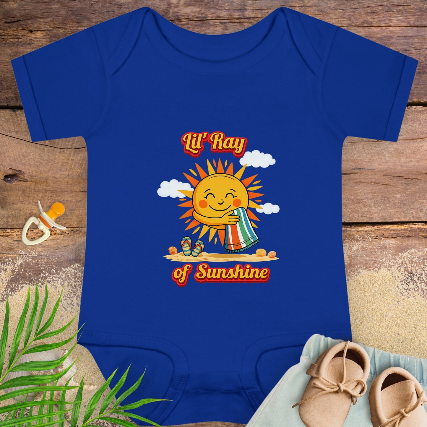 Blue baby onesie onesie with smiling sun beach graphic and text “Lil’ Ray of Sunshine.