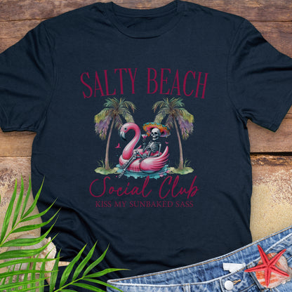 Navy blue t-shirt with 'Salty Beach Social Club' design featuring a flamingo, palm trees, and skeleton on a wooden surface.