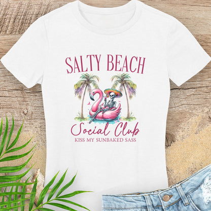 White t-shirt with 'Salty Beach Social Club' design featuring a flamingo and palm trees on a wooden surface.