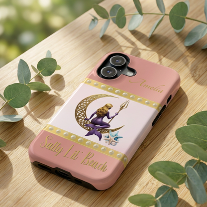 Phone case with a design of a mermaid and crescent moon on a pink background, placed on a wooden surface.
