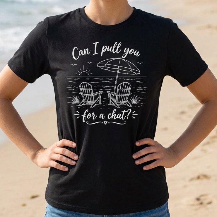 Woman wearing a black t-shirt with a beach graphic and text "Can I pull you for a chat?" on a sandy beach.