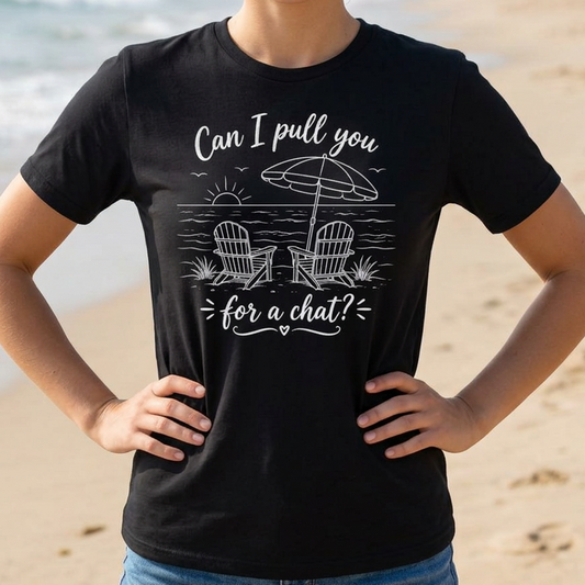Woman wearing a black t-shirt with a beach graphic and text "Can I pull you for a chat?" on a sandy beach.