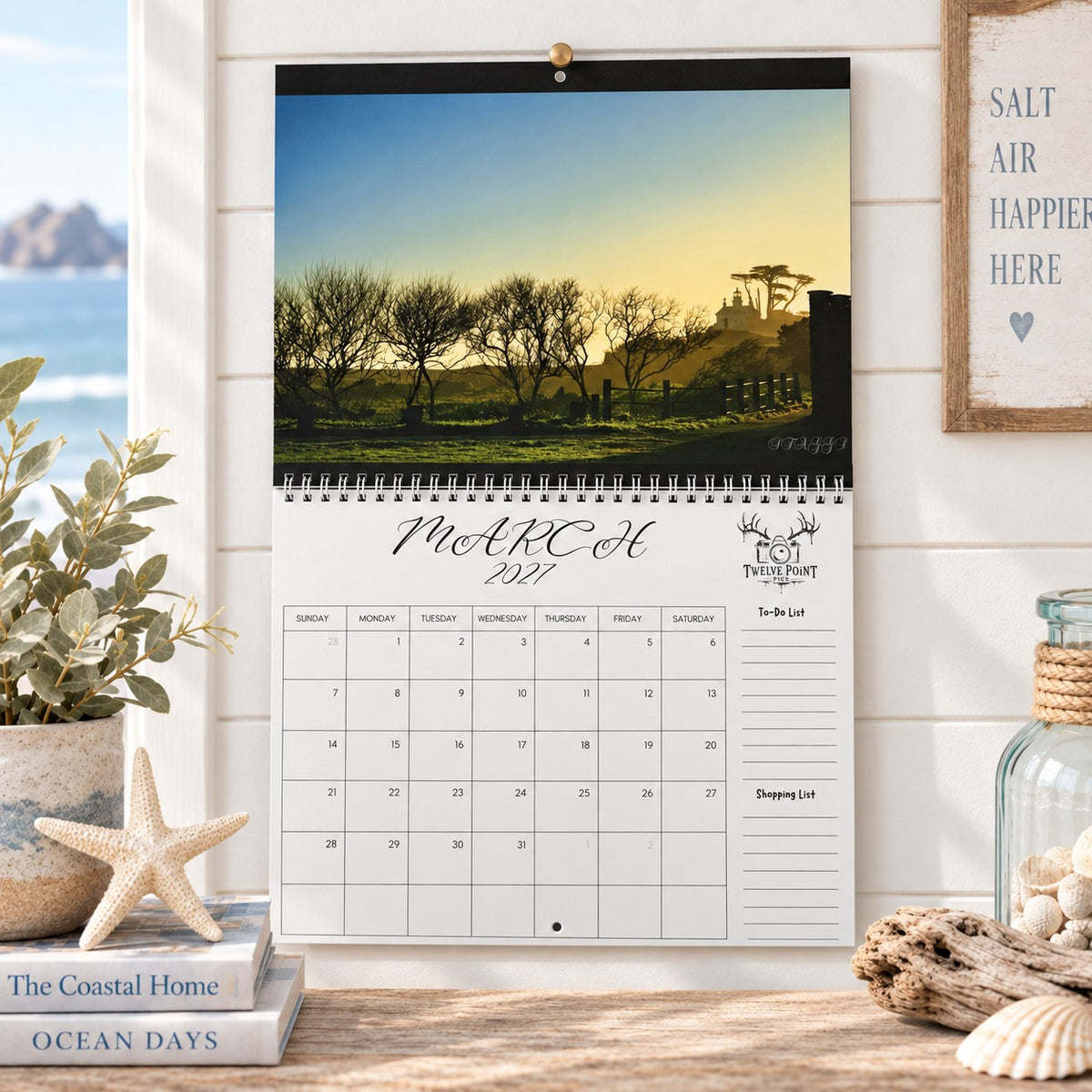 A wall-mounted March 2027 wall calendar monthly planning grid with to-do list and shopping list featuring Twelve Point Pics photography.