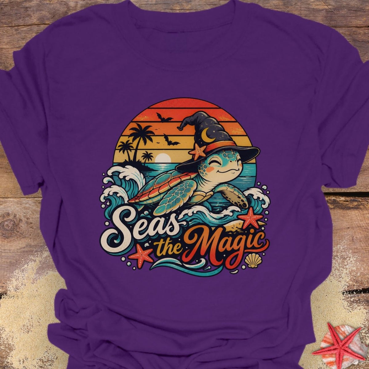 Purple unisex t-shirt with “Seas the Magic” text, a sea turtle wearing a witch hat, ocean waves, sunset, palm trees, bats, and starfish.