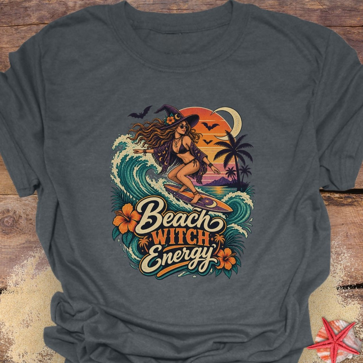 Dark Heather Gray unisex t-shirt with “Beach Witch Energy” text, a witchy surfer girl, ocean wave, sunset, crescent moon, bats, palm trees, and tropical flowers.
