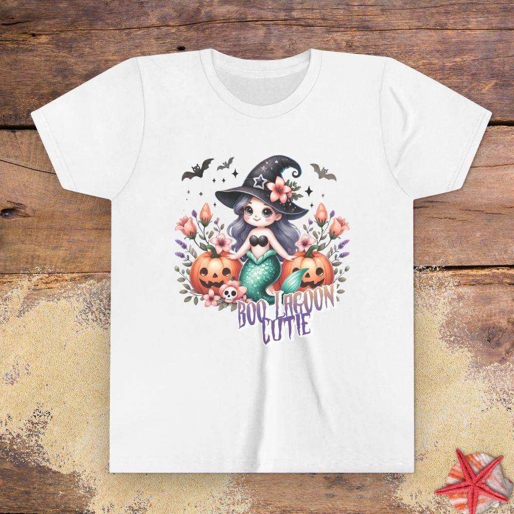 White kids t-shirt with “Boo Lagoon Cutie” text, a cute witchy mermaid, pumpkins, bats, and flowers.