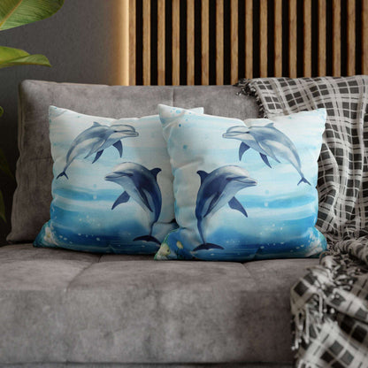 Two decorative pillow cover with a watercolor design of two dolphins in the water with flowers along the bottom edges showing the double-sided print.