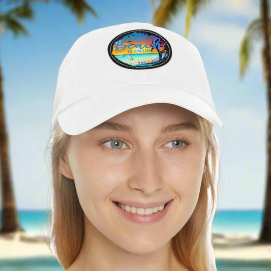 White hat with a leather patch with picture of beach scene and text The beach is calling and I must go.