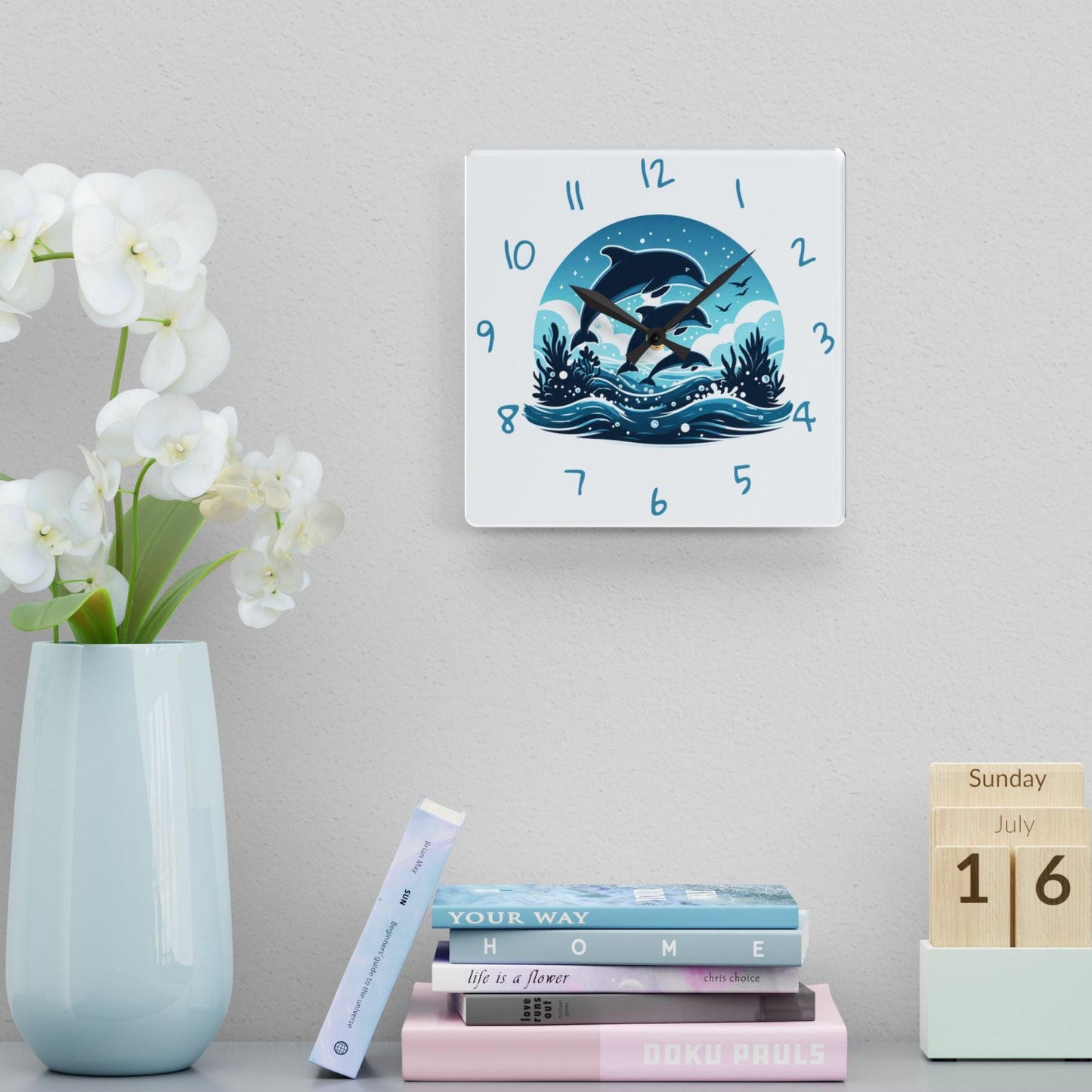 Wall clock with swimming dolphins design on a shelf with books and a vase.