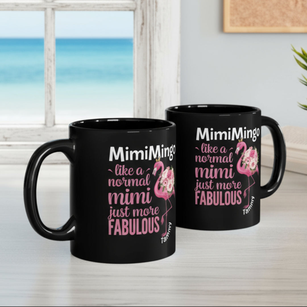 Two black mugs with flamingo graphics and text on a desk.