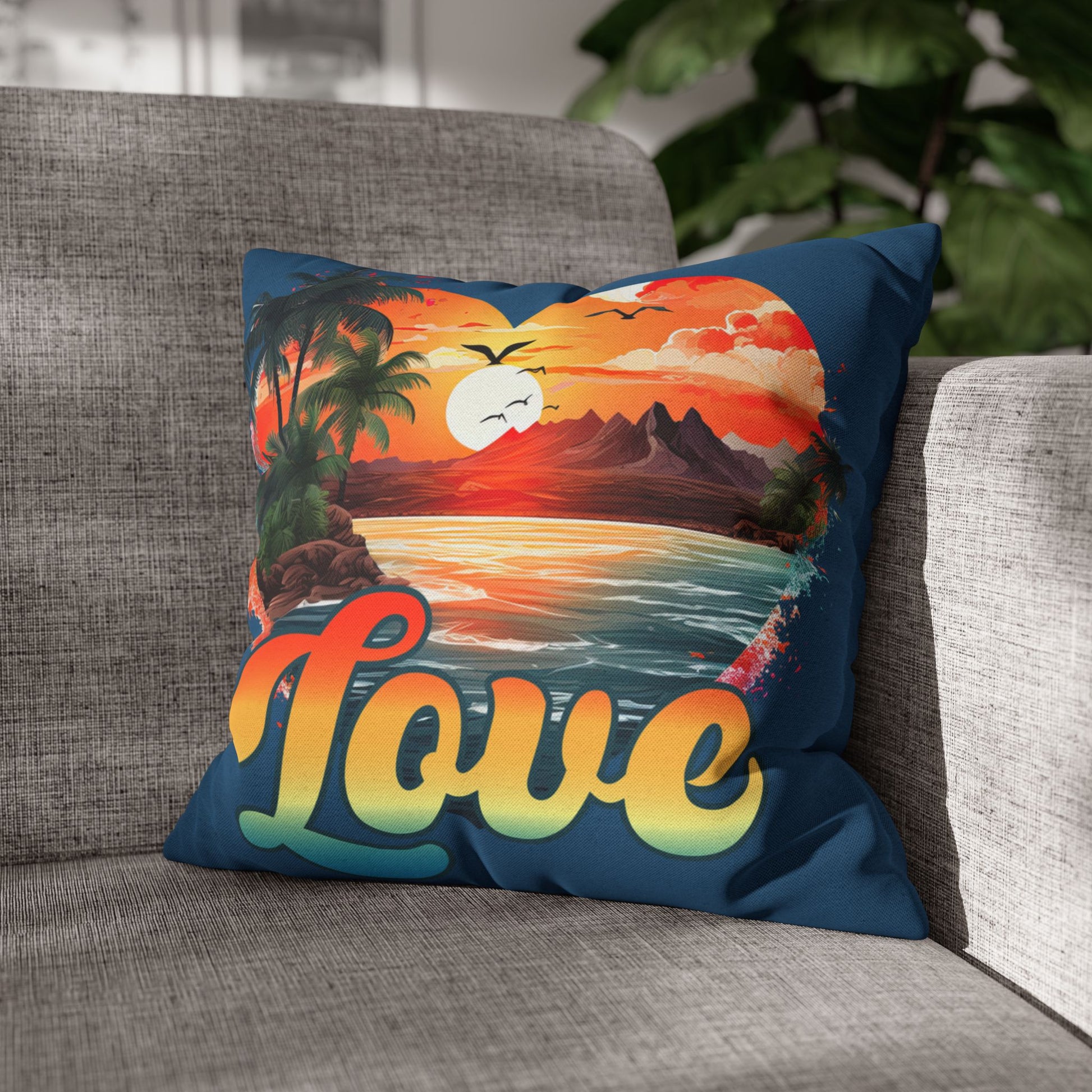 Decorative 16" x 16" blue pillow with a sunset heart design and 'love' text on a gray couch.