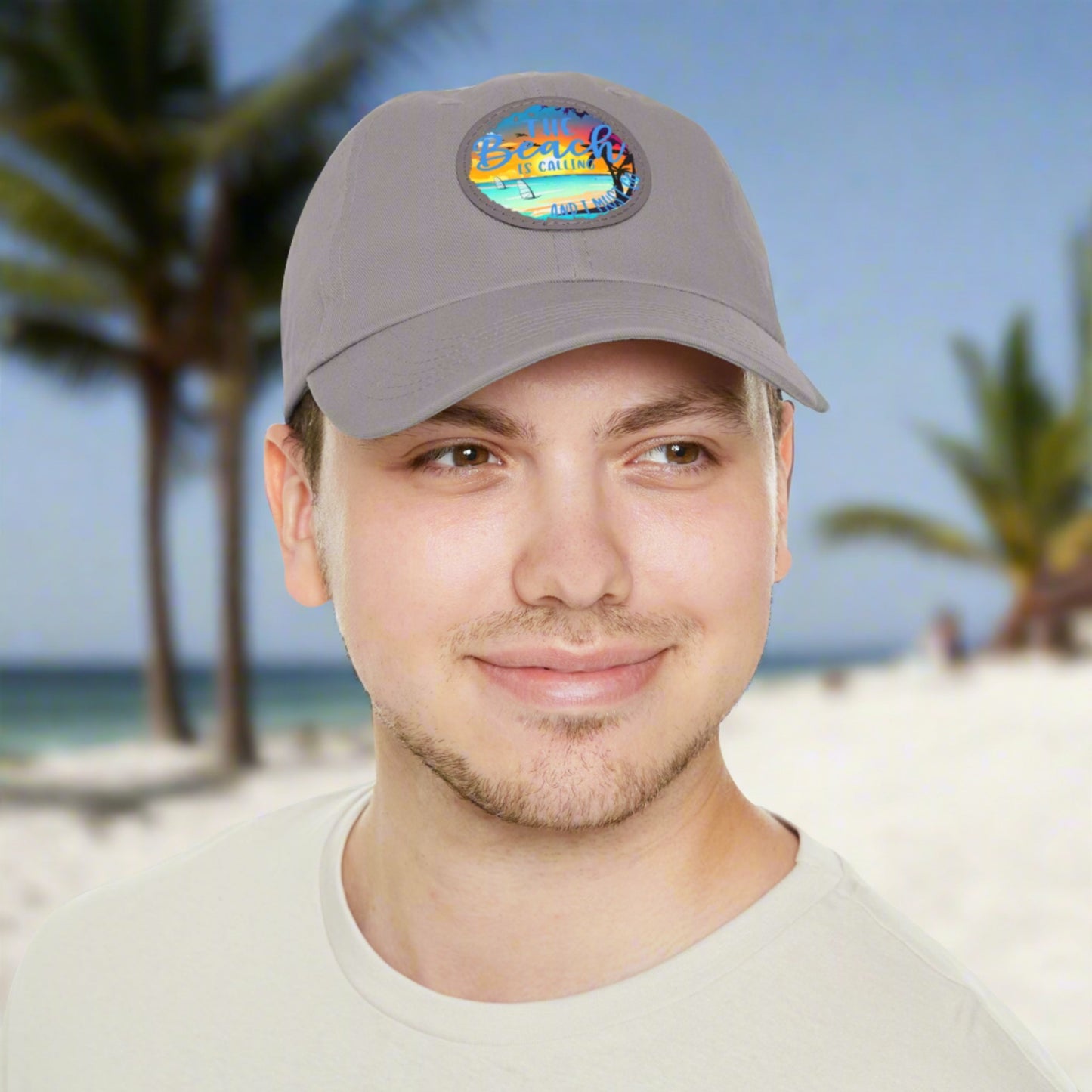 Gray hat with a leather patch with picture of beach scene and text The beach is calling and I must go.