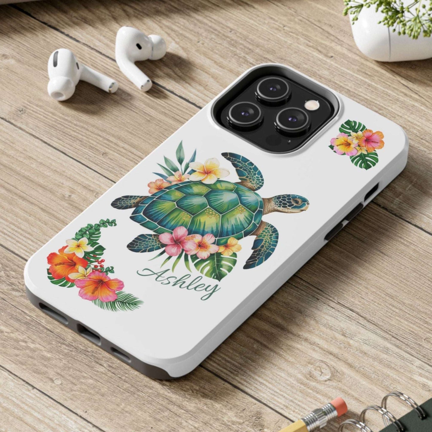 iPhone 14 case with a white background and a sea turtle with hibiscus flowers, with more hibiscus flowers around the sides.