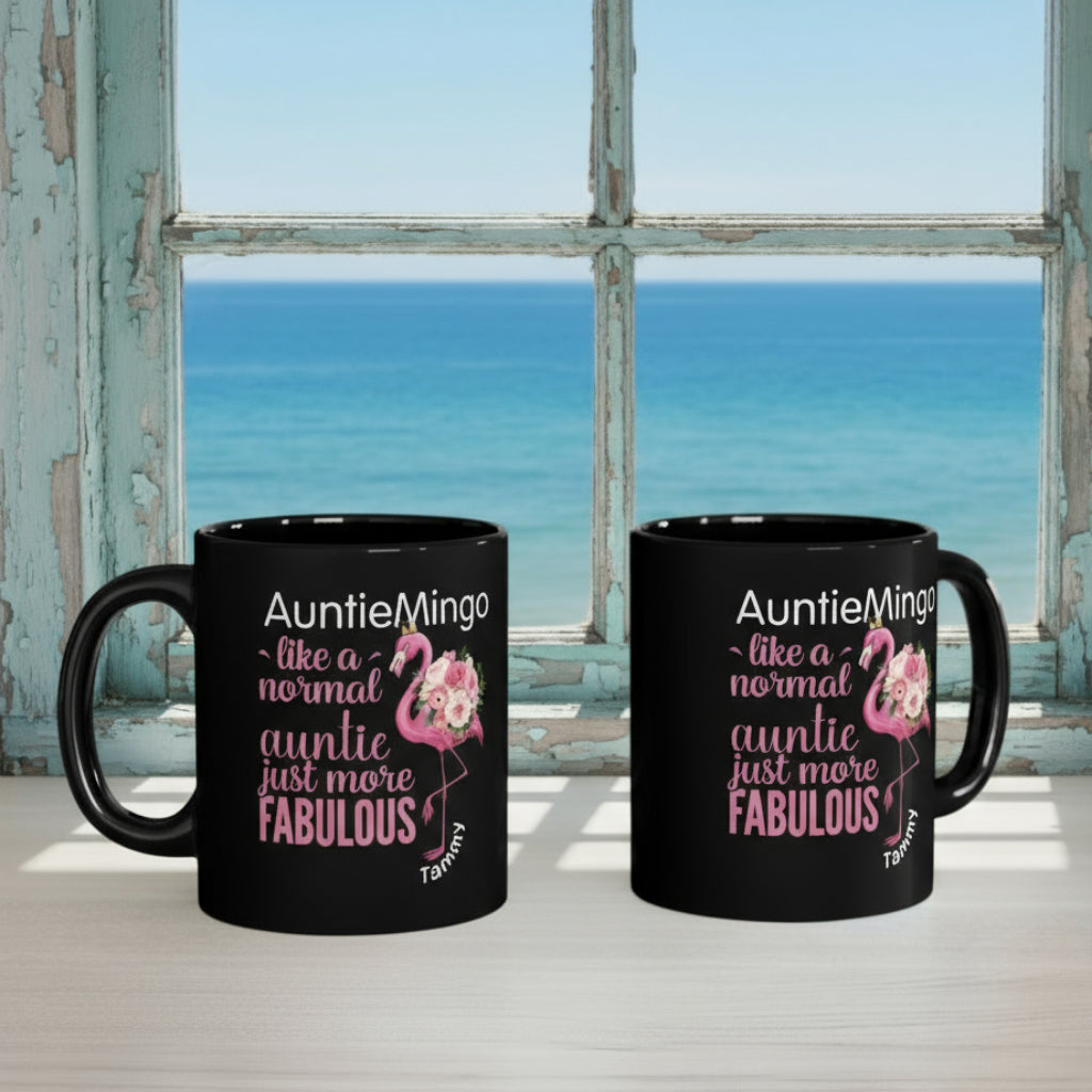 Two black mugs with flamingo design and text on a desk.