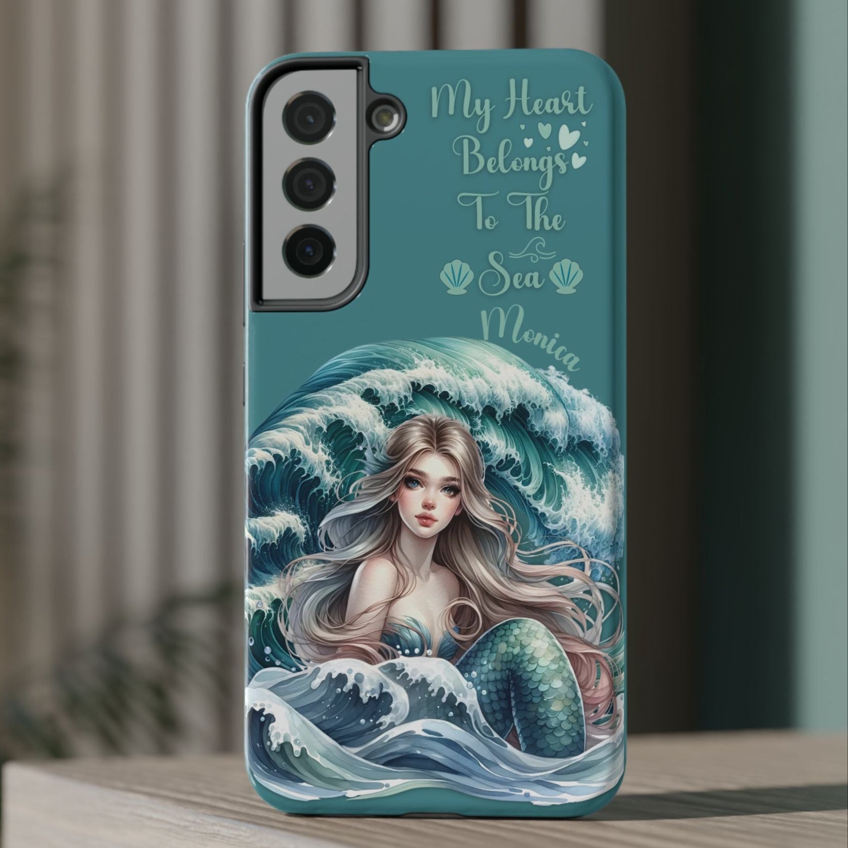 Phone case with mermaid design and text on a wooden surface