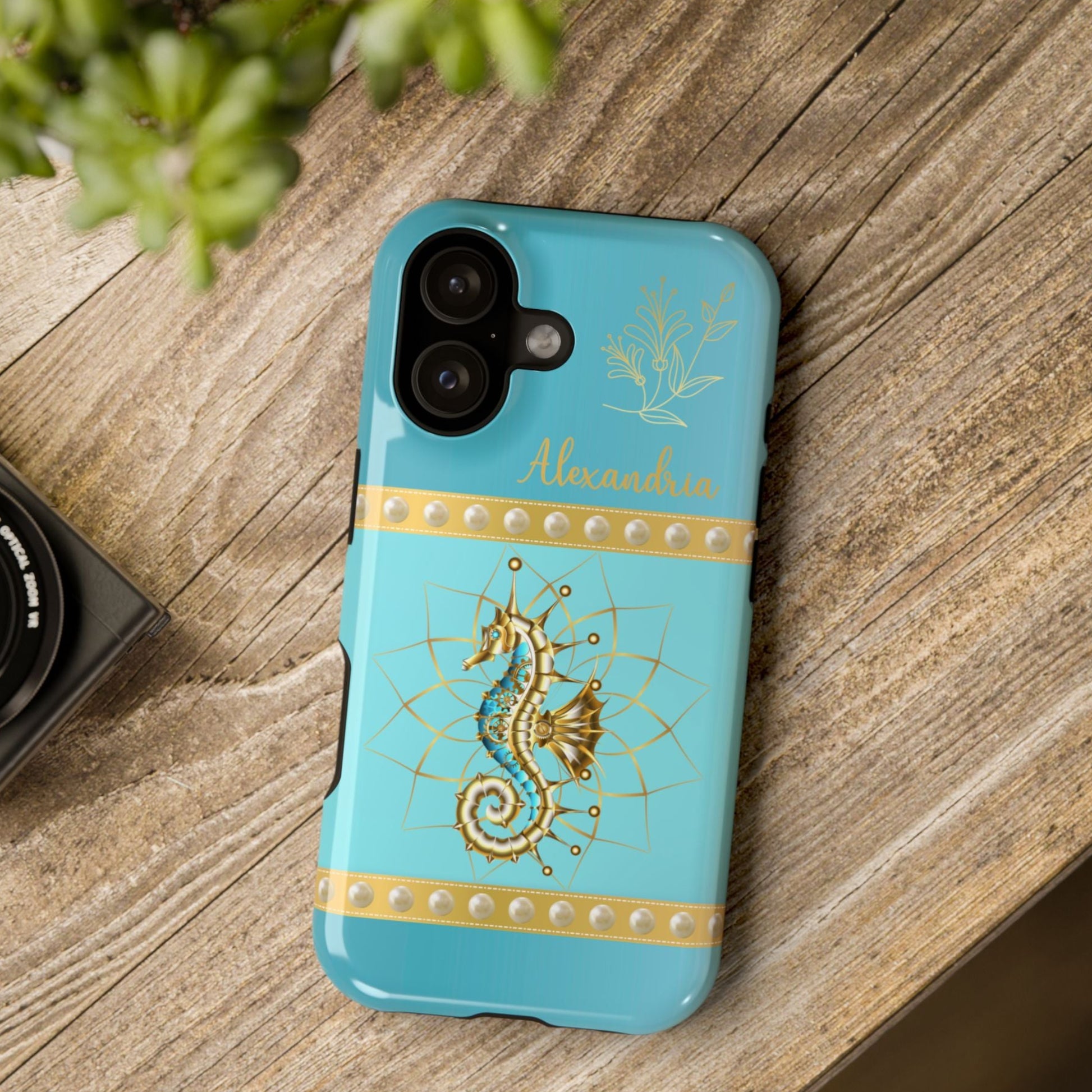Turquoise phone case with gold seahorse design on a wooden surface