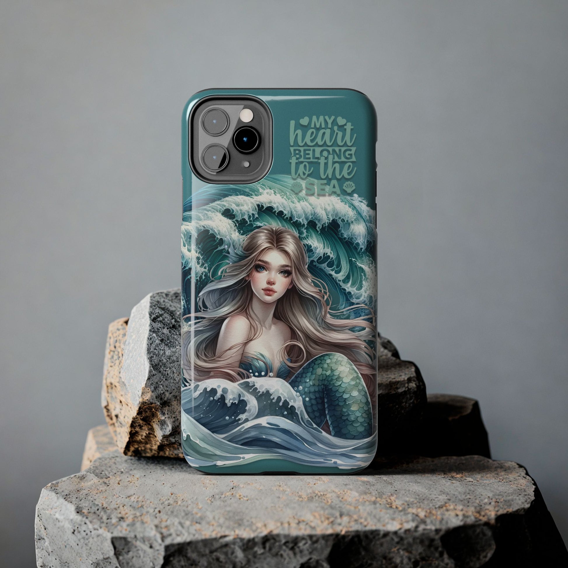 Phone Case with Flowy mermaid with ocean wave behind and text My Heart Belongs to the Sea against rock