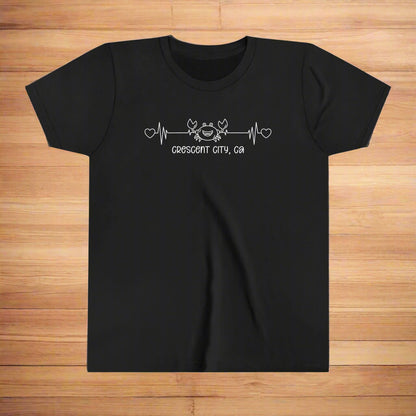 Black Youth t-shirt with a smiley crab on a heartbeat line with hearts at both ends and “Crescent City, CA” underneath the design.
