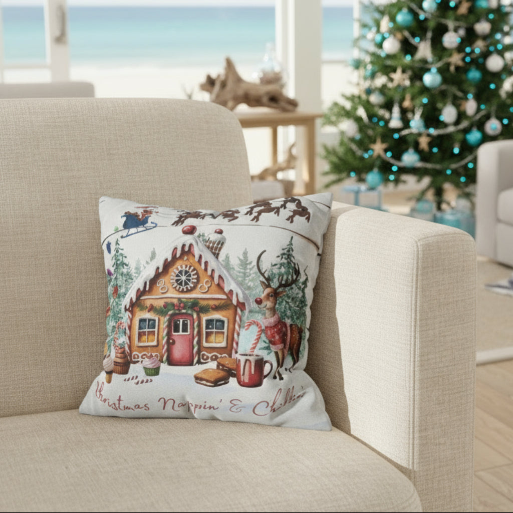 Decorative pillow with Christmas design featuring a gingerbread house and reindeer on a gray couch.