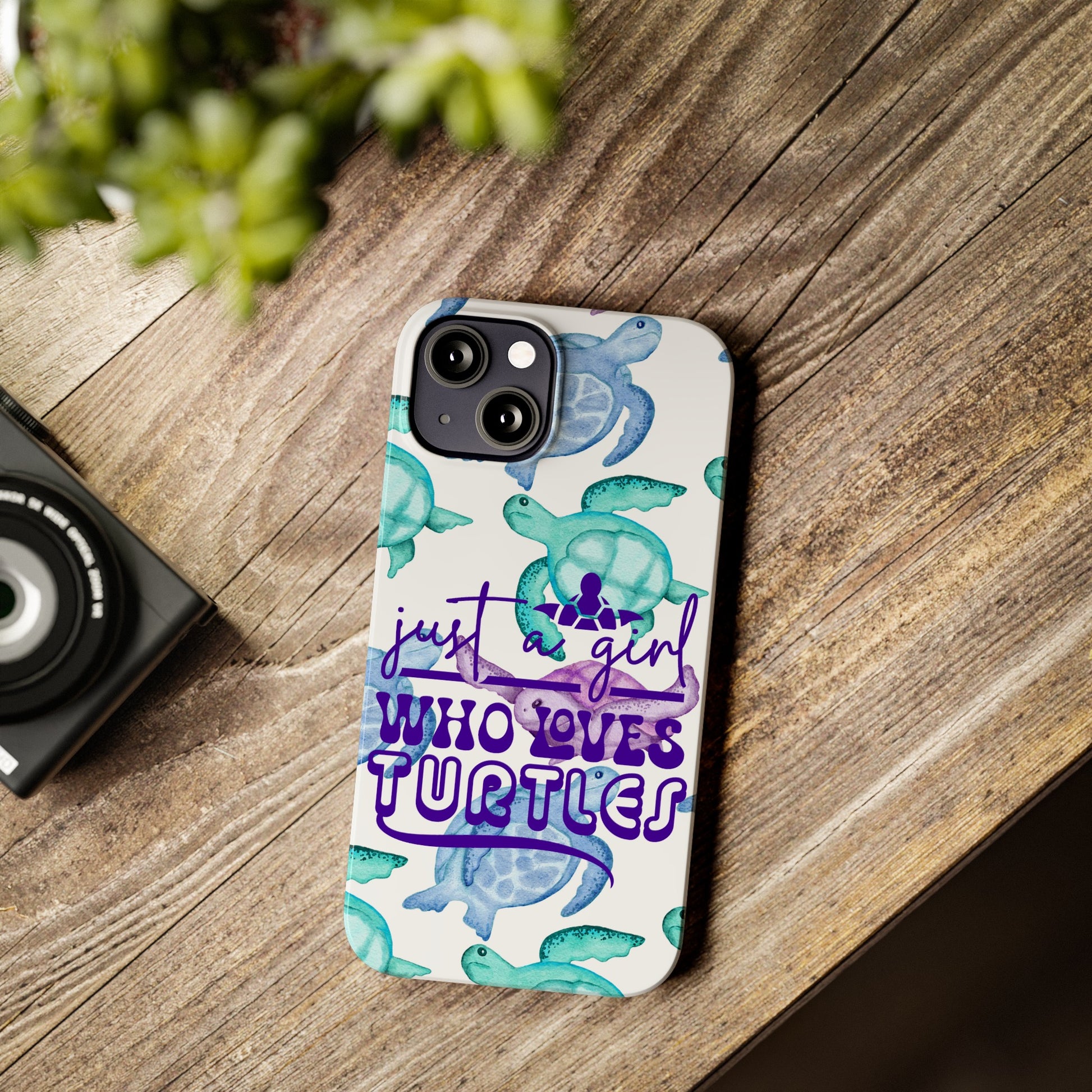 Iphone case with turquoise, blue and purple sea turtles that says  Just a Girl Who Loves Sea turtles laying on wood desk