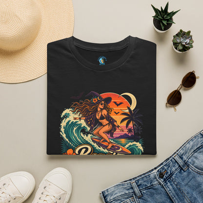 Folded Black unisex t-shirt with “Beach Witch Energy” text, a witchy surfer girl, ocean wave, sunset, crescent moon, bats, palm trees, and tropical flowers.