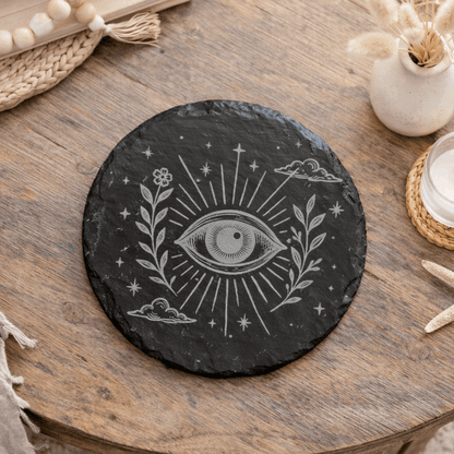 Decorative black slate coaster with celestial eye and floral design.