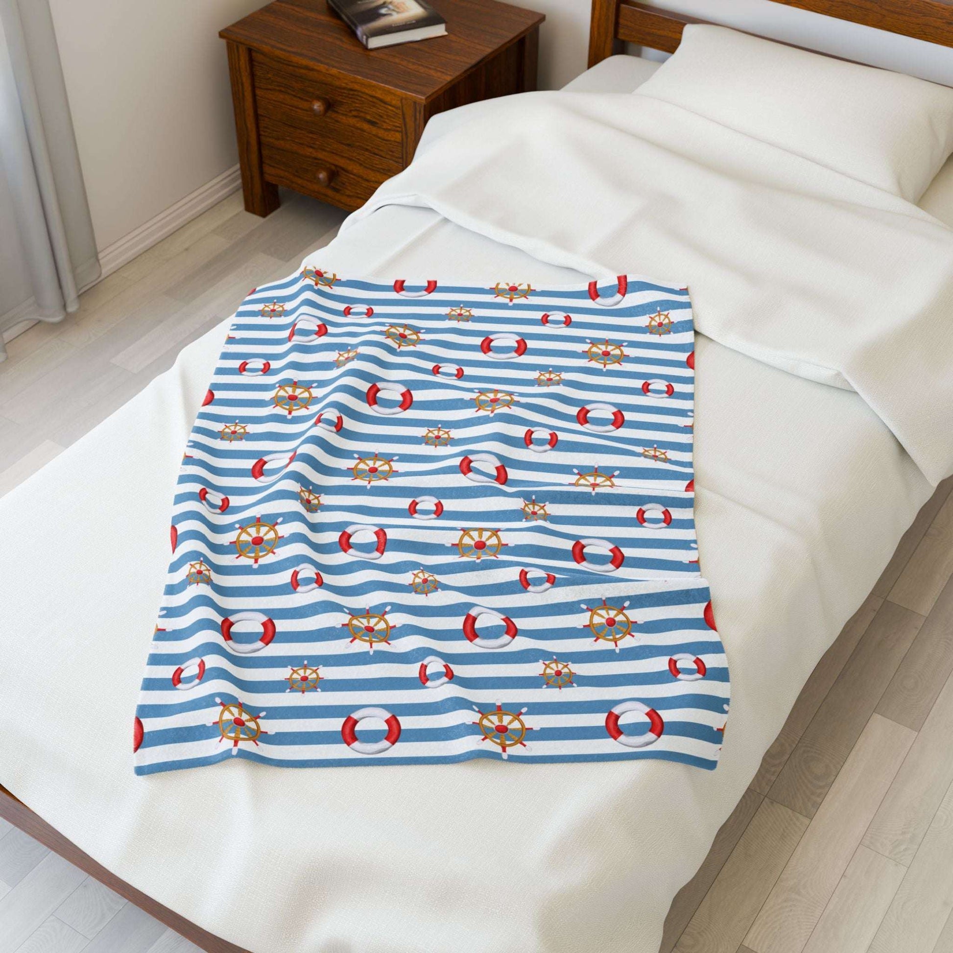 Nautical-themed blanket with blue stripes and red life buoys on a bed.