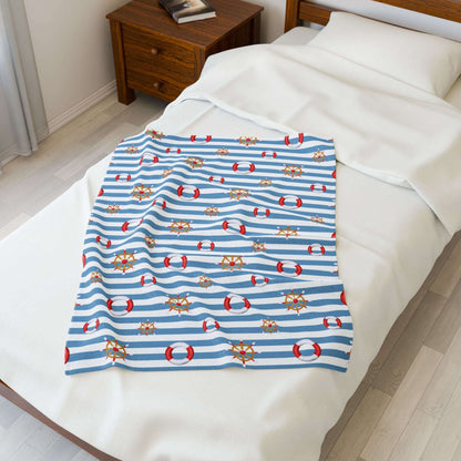Nautical-themed blanket with blue stripes and red life buoys on a bed.