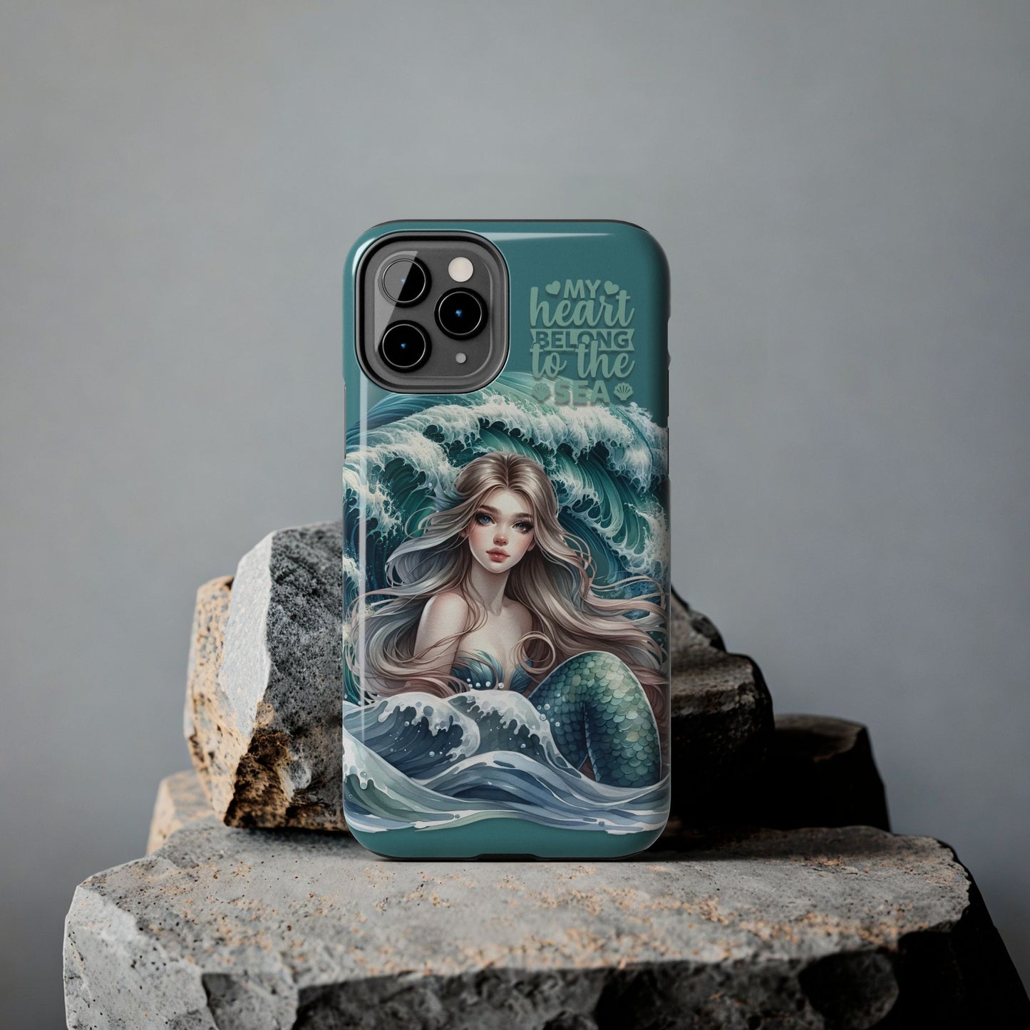 Phone Case with Flowy mermaid with ocean wave behind and text My Heart Belongs to the Sea against rock