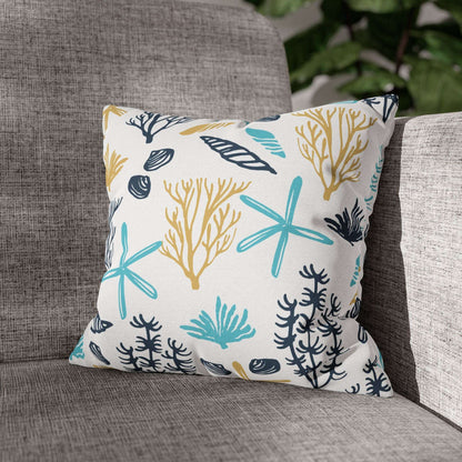 Decorative 14" x 14" white pillow with coral and starfish pattern on a gray couch.