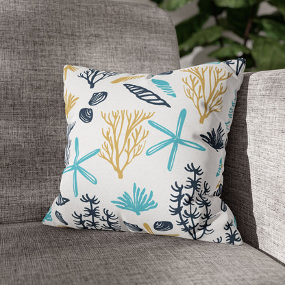 Decorative 14" x 14" white pillow with coral and starfish pattern on a gray couch.