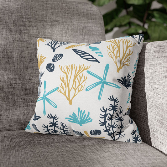 Decorative 14" x 14" white pillow with coral and starfish pattern on a gray couch.