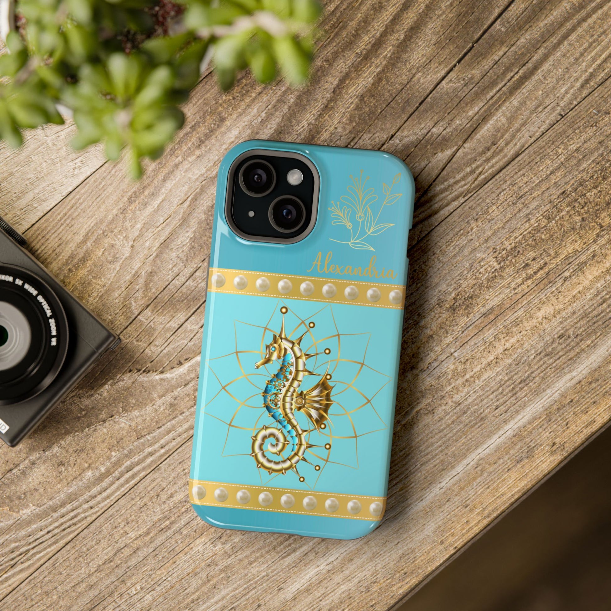Turquoise phone case with gold seahorse design on a wooden surface