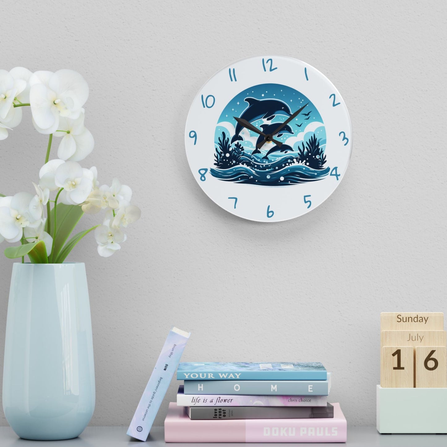 Wall clock with swimming dolphins design on a shelf with books and a vase.