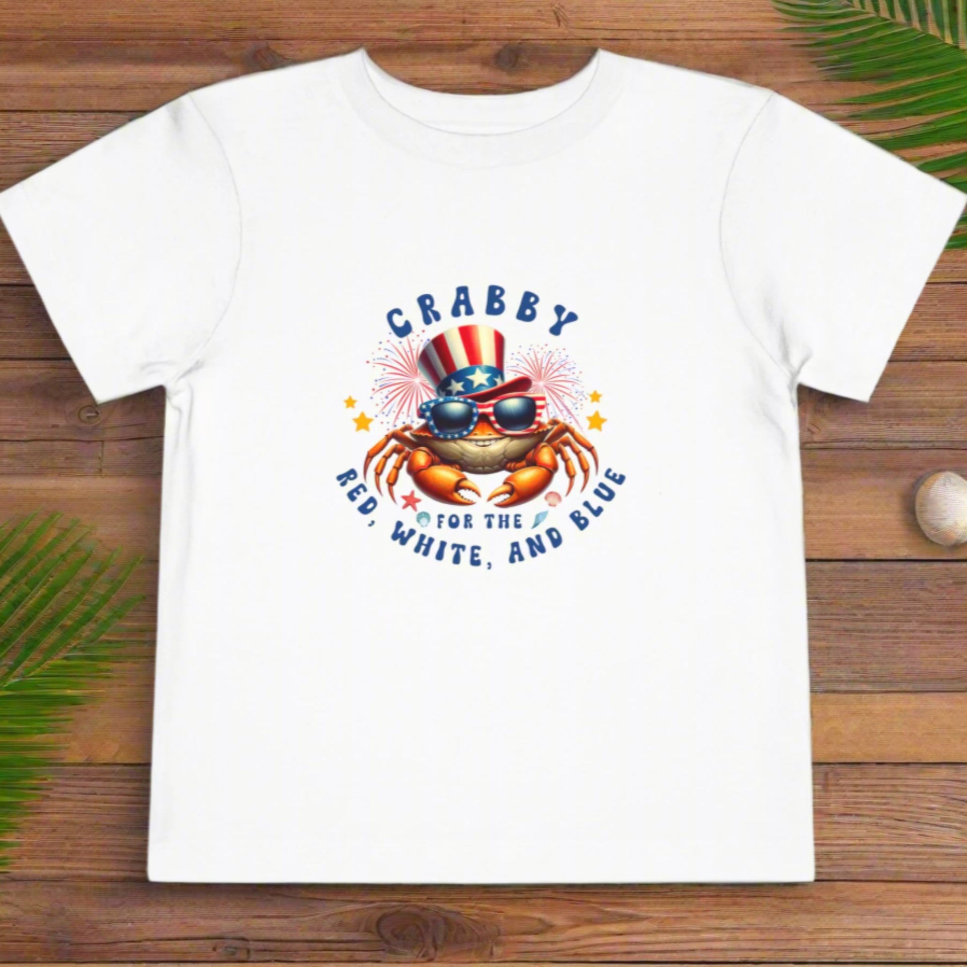 White t-shirt with a colorful graphic of a crab wearing an American flag hat and sunglasses, with text 'CRABBY RED, WHITE, AND BLUE' on a white background.