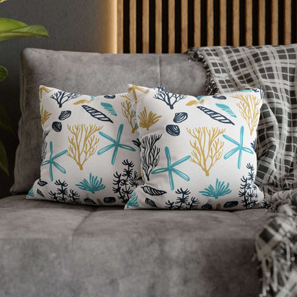 Two 14" x 14" white pillows with coral and starfish pattern on a gray couch.