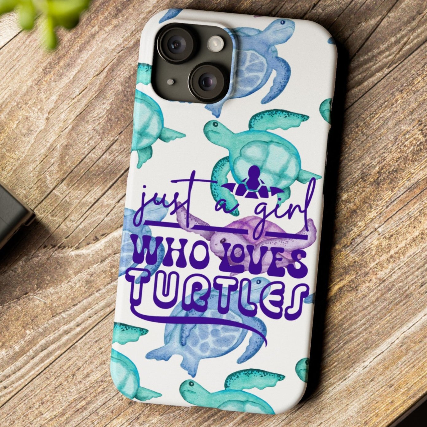 Iphone case with turquoise, blue and purple sea turtles that says  Just a Girl Who Loves Sea turtles laying on wood desk