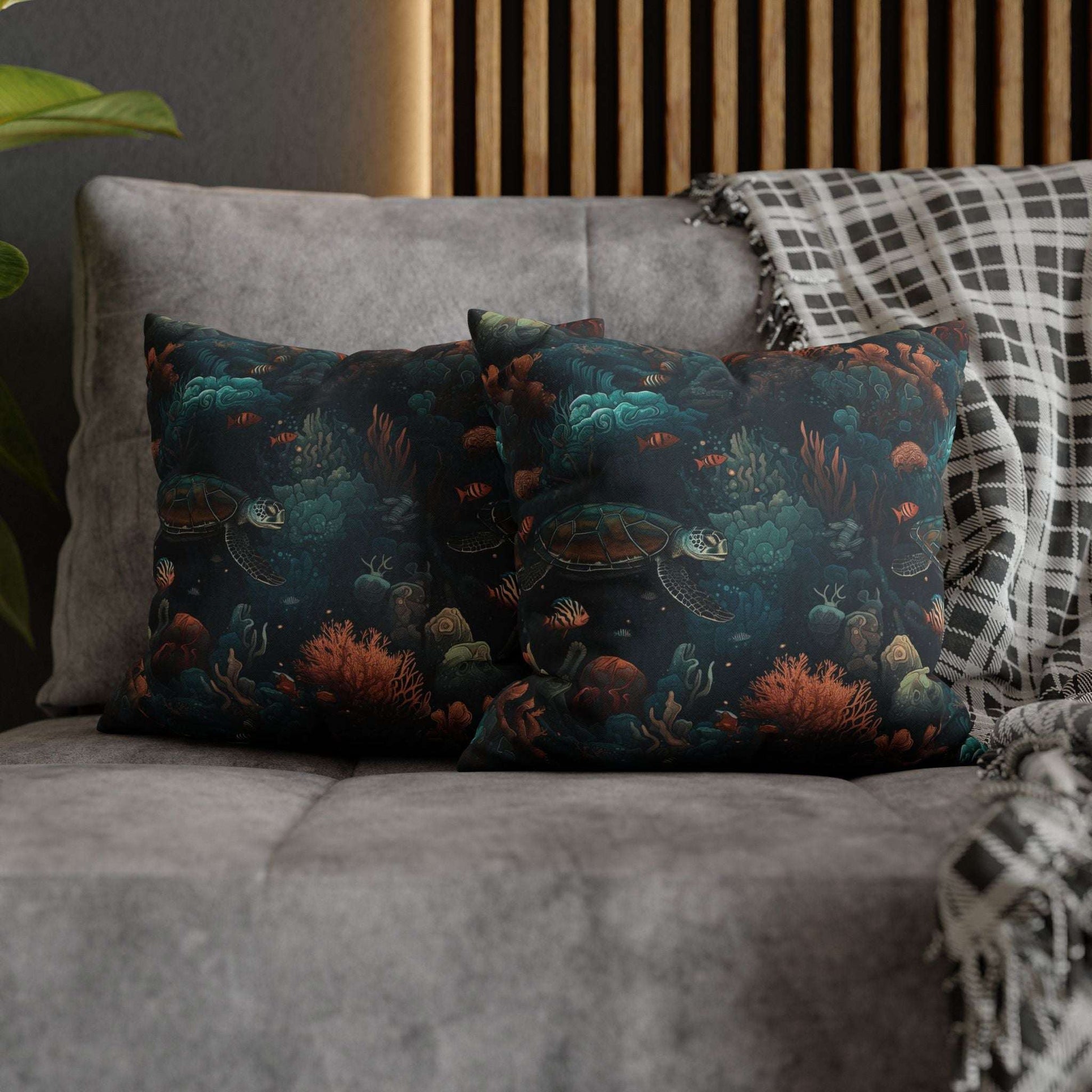 14" x 14" two decorative pillows with underwater scene with sea turtles on a gray couch.