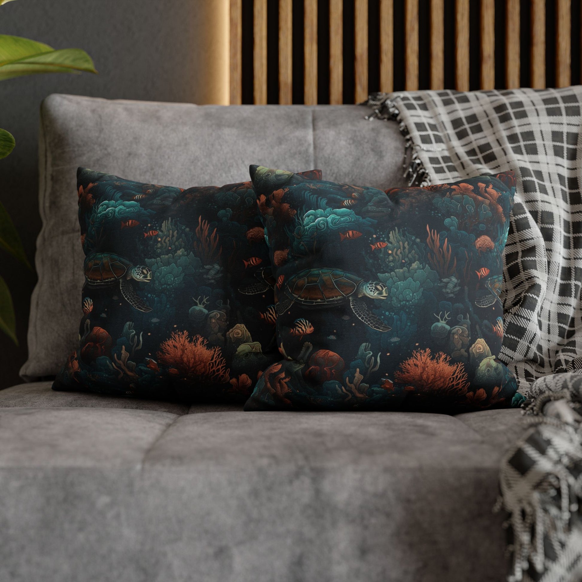 14" x 14" two decorative pillows with underwater scene with sea turtles on a gray couch.