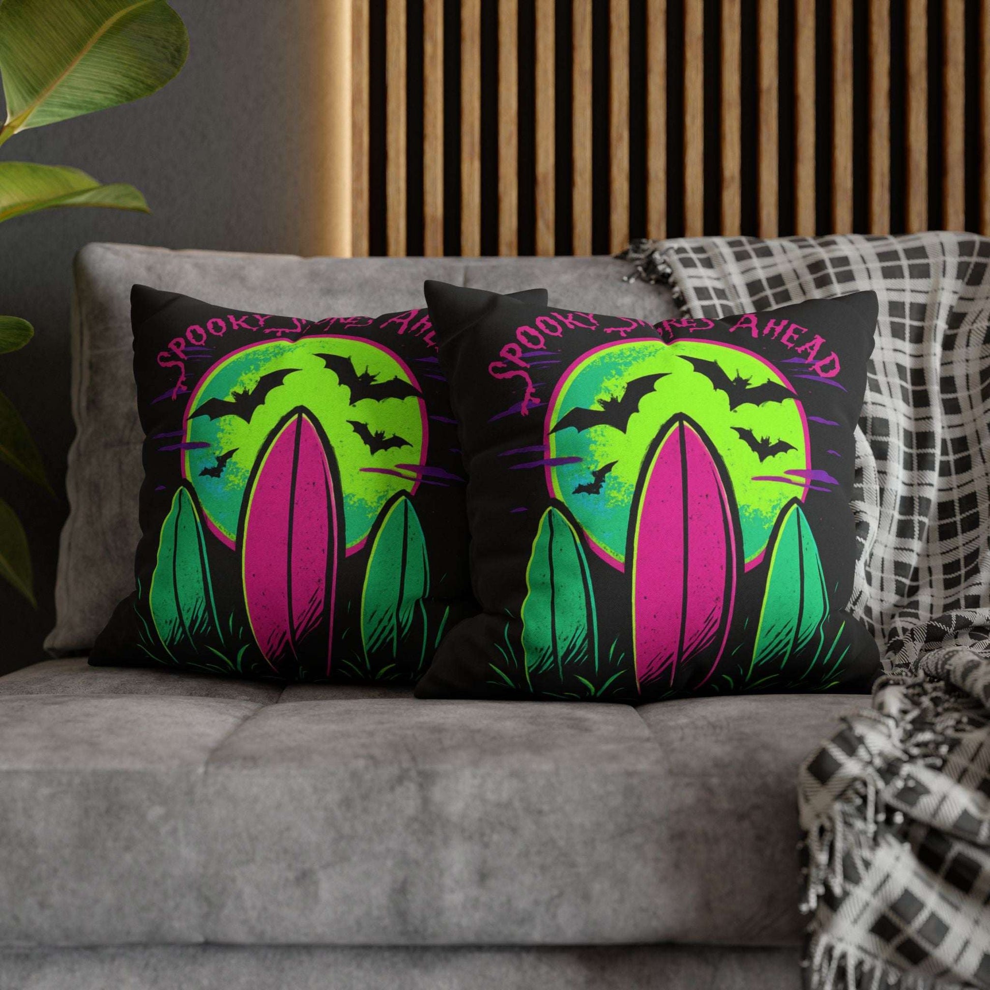 Halloween-themed decorative pillow cases with surfboards and text 'Spooky Shores Ahead' on a couch.
