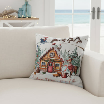 Decorative Christmas pillow with gingerbread house design on a couch.