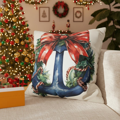Decorative pillow with a Christmas Blue anchor and wreath behind it and red bow on a couch.