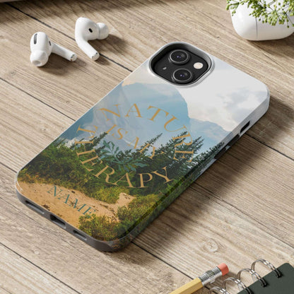 Phone case with nature design on a wooden desk with laptop, earbuds, and notebook.
