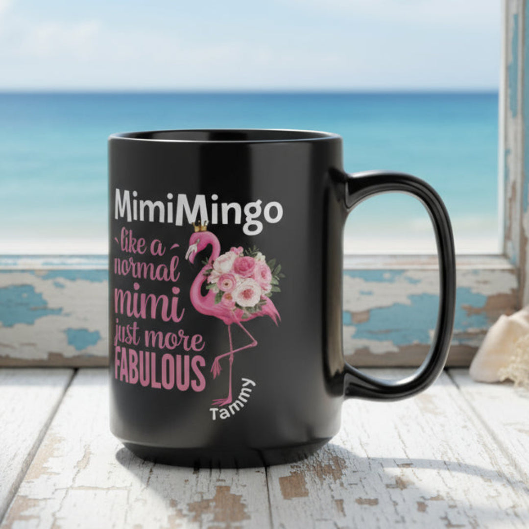 Black mug with flamingo design and text on a white surface