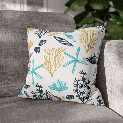 Decorative 16" x 16" white pillow with coral and starfish pattern on a gray couch.
