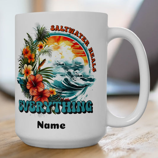 White 15 oz. ceramic mug with an ocean scene surrounded by tropical flowers with the text Saltwater Heals Everything and the word Name underneath where it can be personalized.