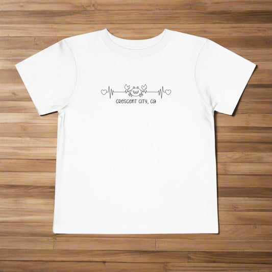 White Toddler t-shirt featuring a smiley crab on a heartbeat line with hearts at both ends and the text “Crescent City, CA” underneath.
