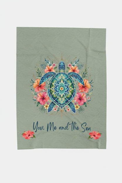 An ultra-soft plush 50x60" blanket featuring a vibrant mandala sea turtle surrounded by tropical hibiscus flowers with the phrase "You, Me and the Sea" on a sage-green background.