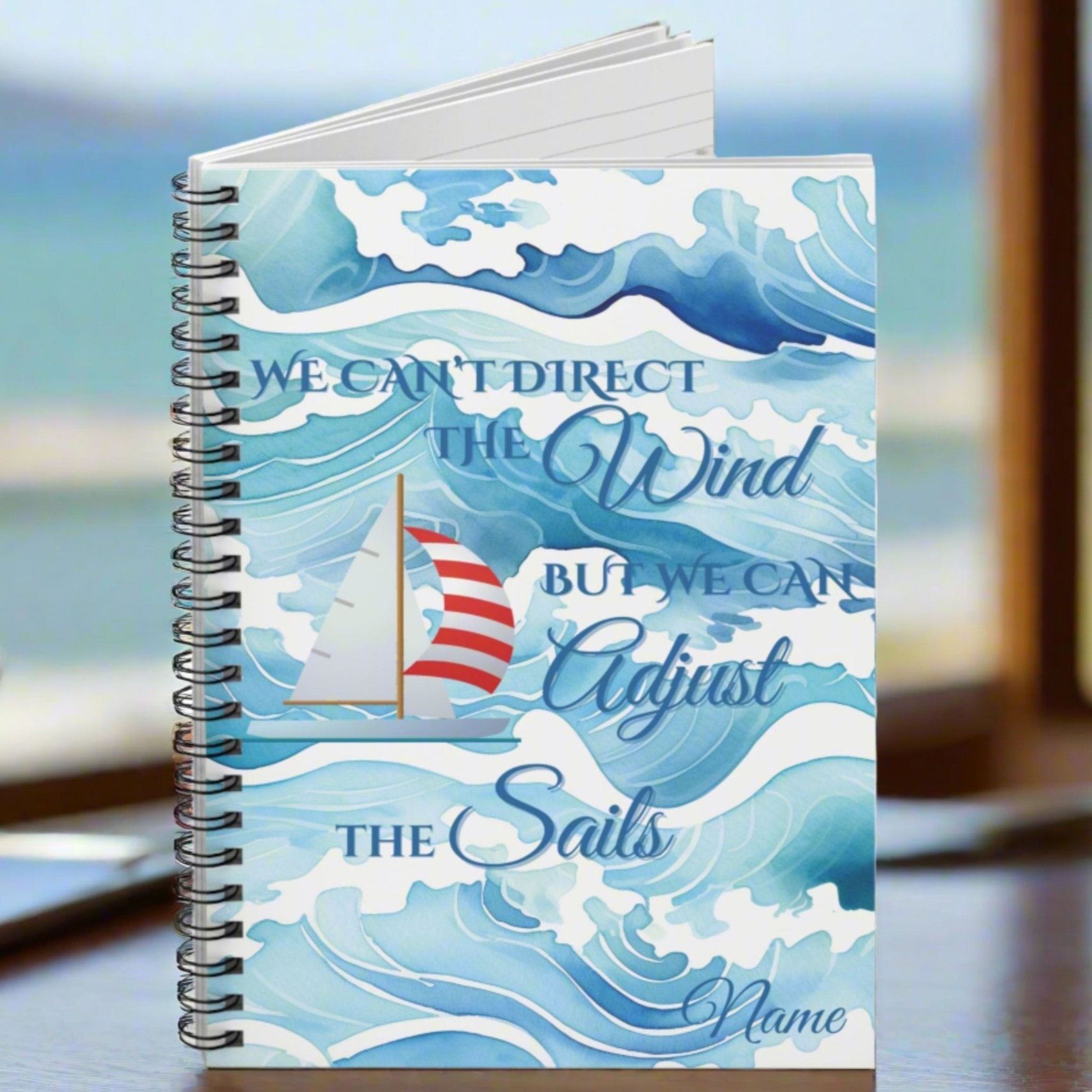 Sprial-bound notebook with waves and red and white sailboat and text We Can't Direct the Winds But We can adjust the sails.